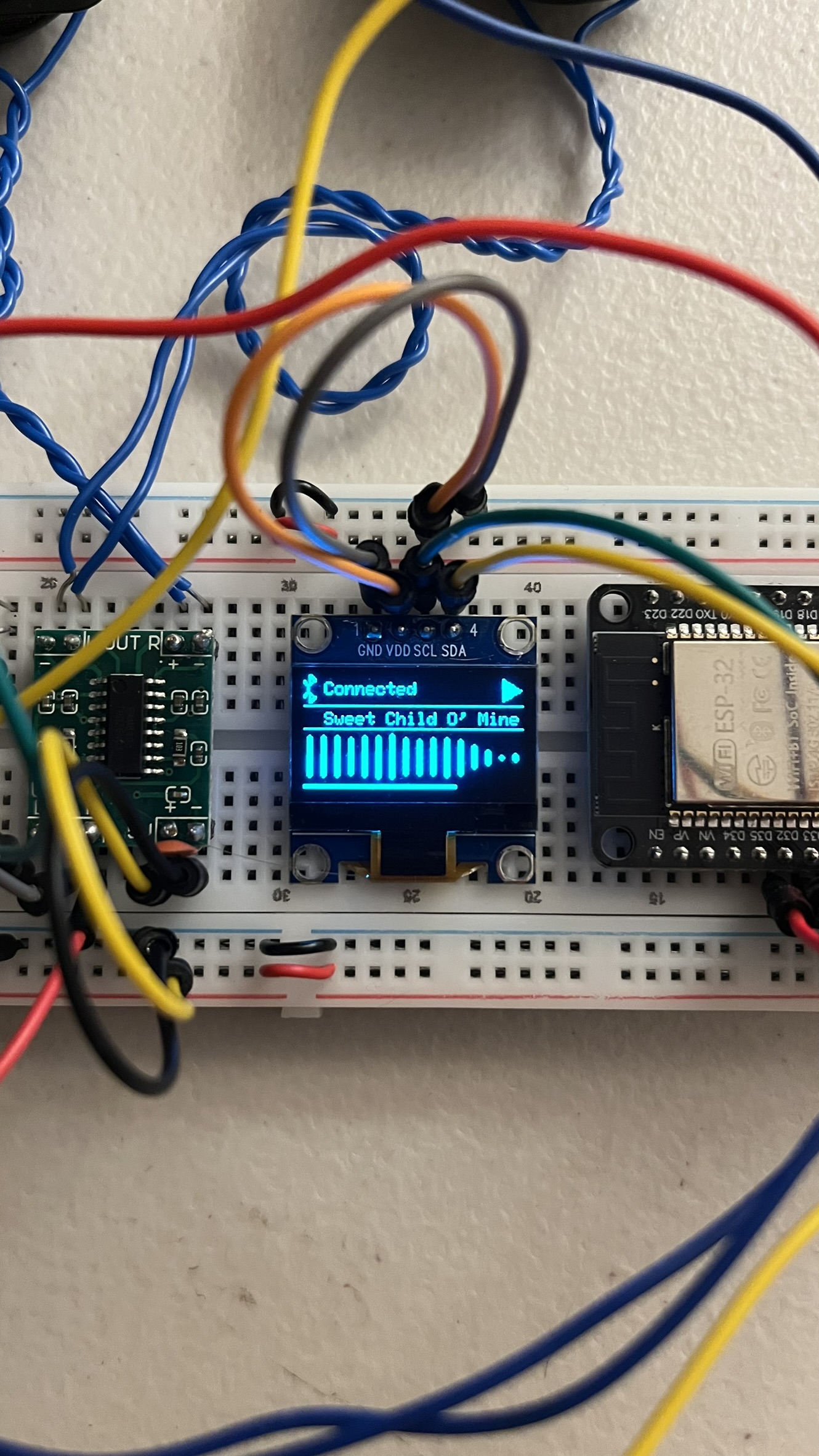 OLED close-up showing connected status, track title, and live FFT spectrum