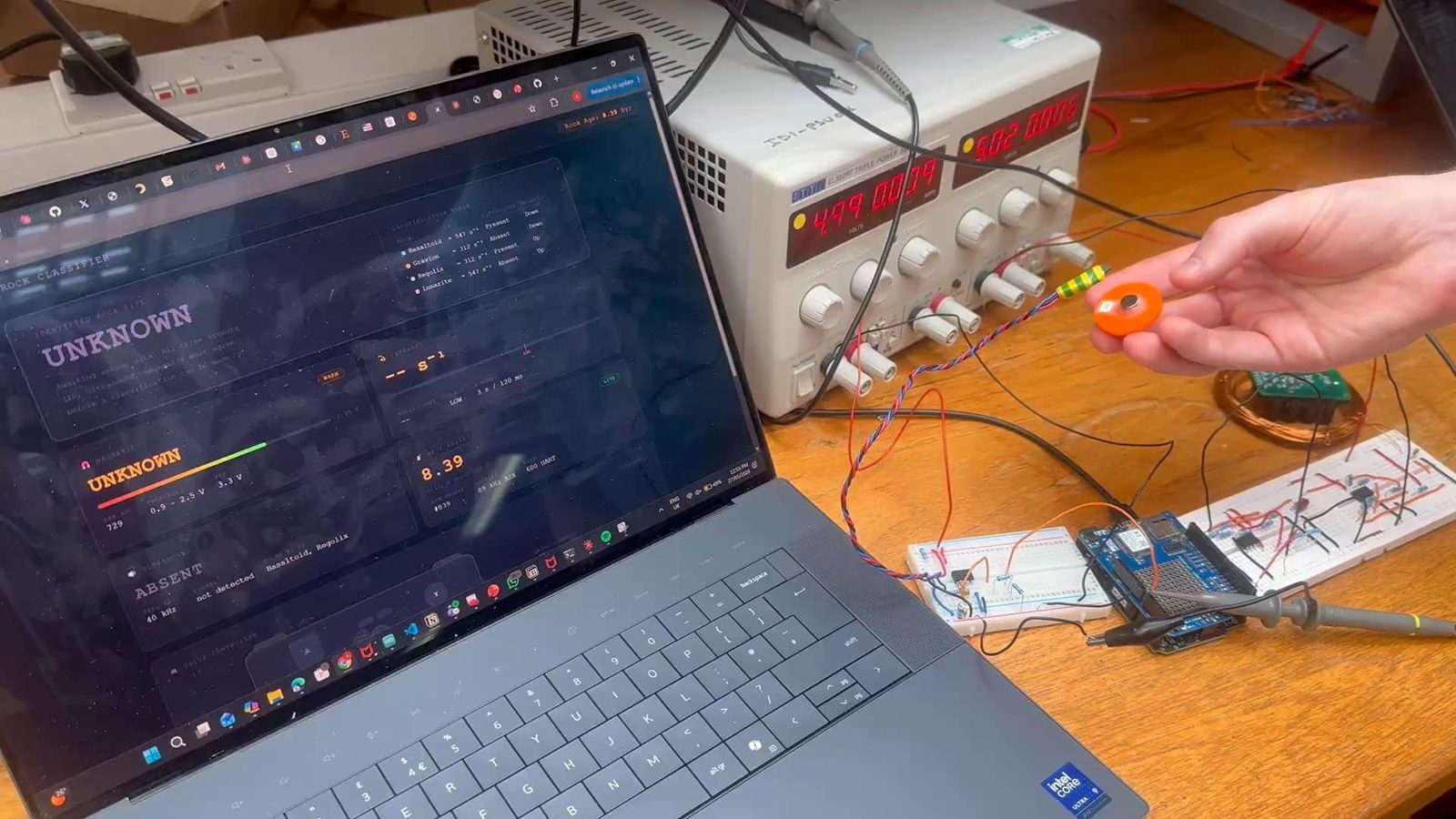 Debugging a sensor front end on the bench: oscilloscope, breadboard prototype, and a rock’s internal magnet and RF coil