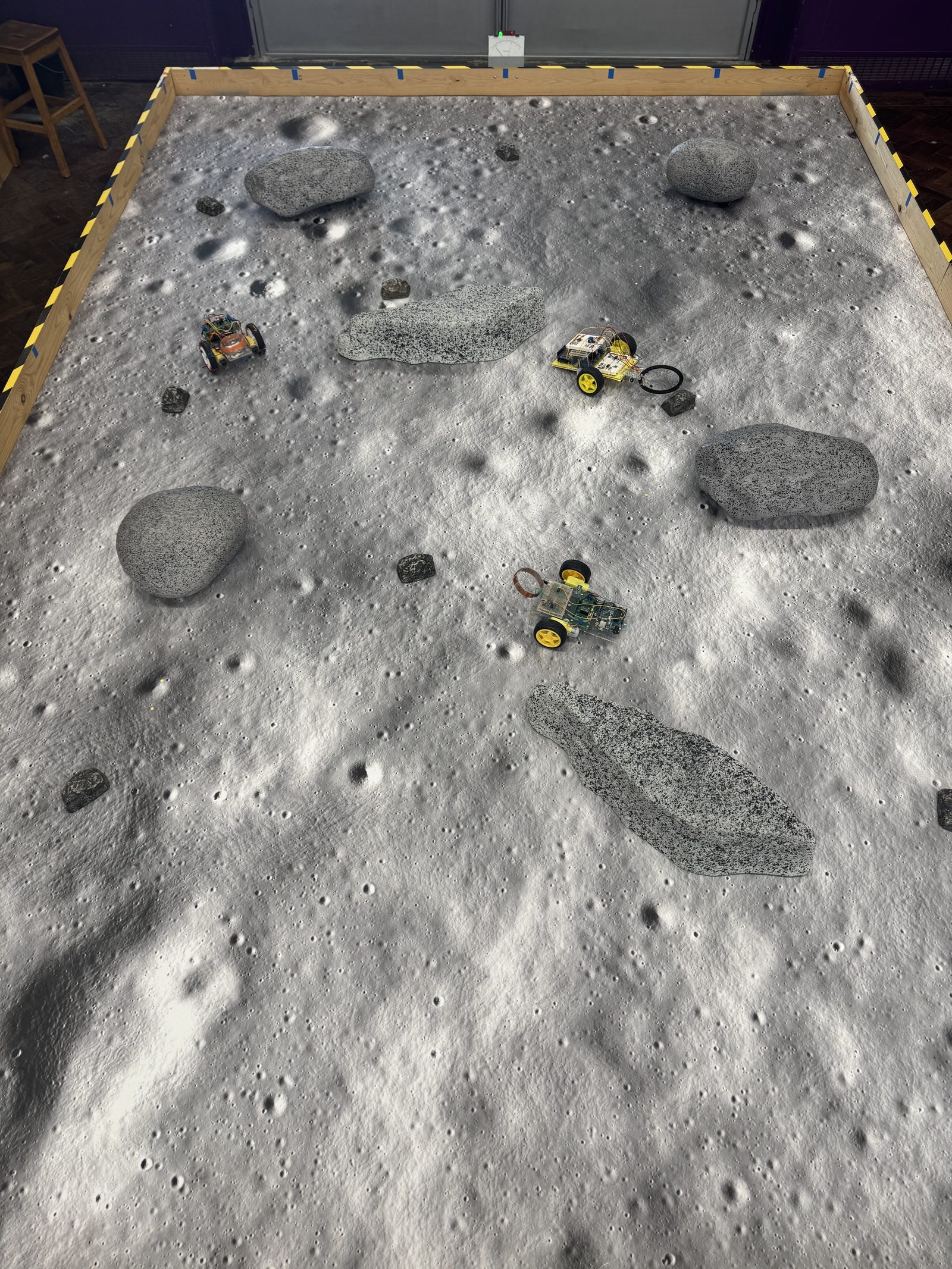 Overhead view of the test arena: painted foam rocks and multiple rovers navigating the surface at once